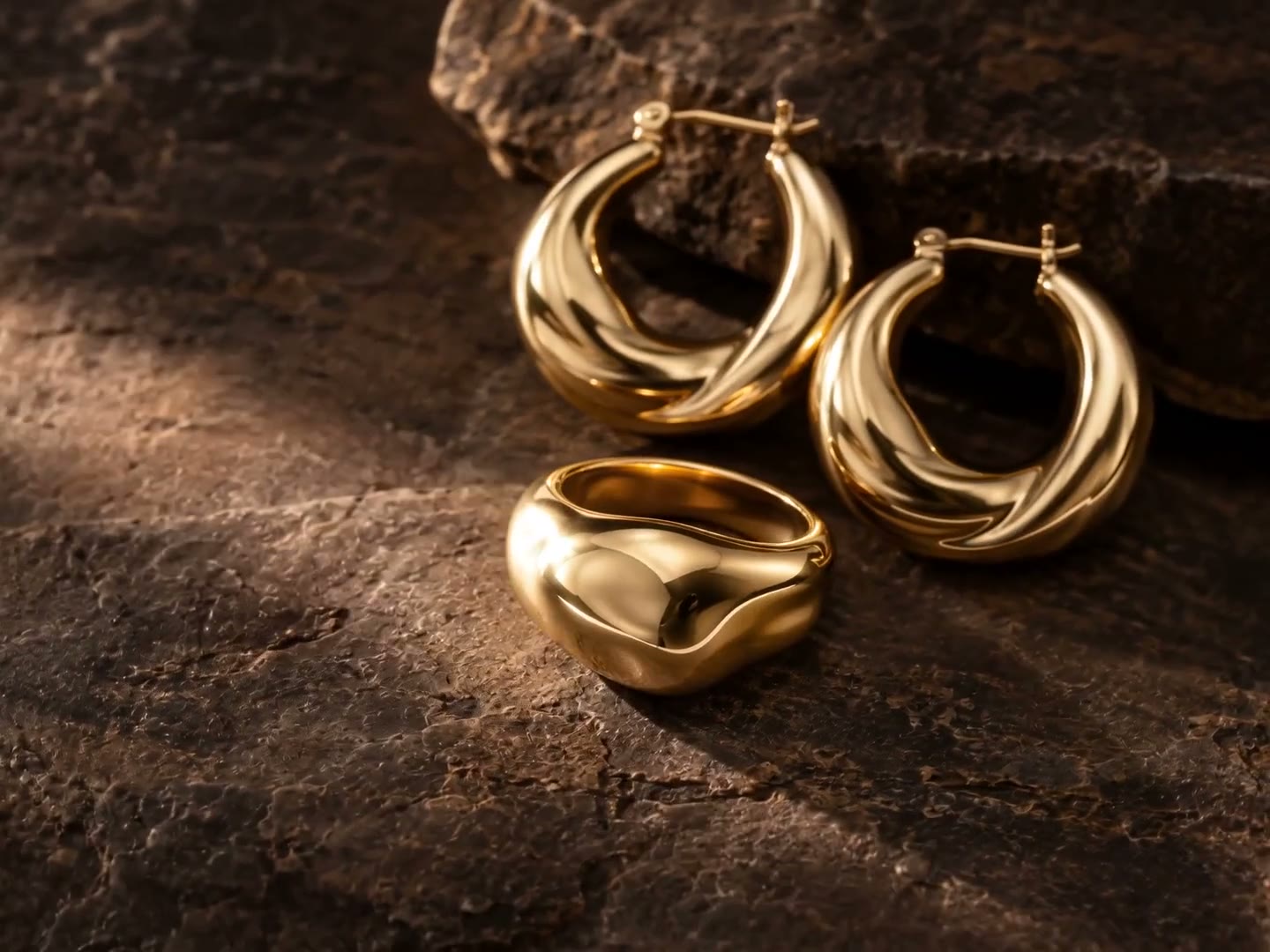 Sculptural gold jewellery on dark textured stone